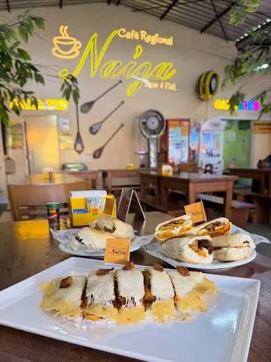 Tapiocas recheadas e sanduíches servidos no Naíza, com o letreiro em neon ao fundo